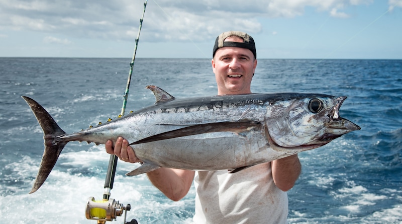 man holds large tuna fish trophy