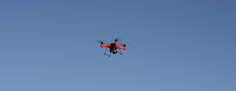 red waterproof drone flies in blue sly