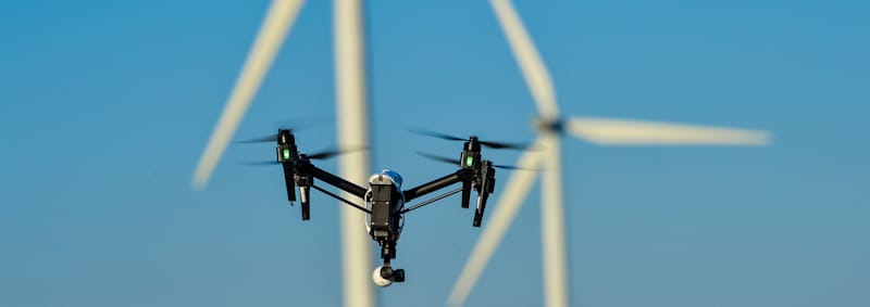 drone flies in front of windmills