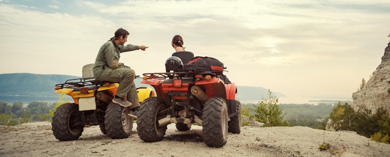 couple lookout cliff sitting on ATVs