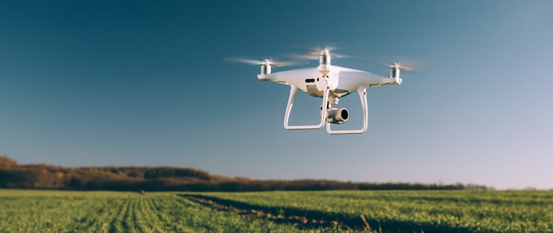 white drone flies on green field