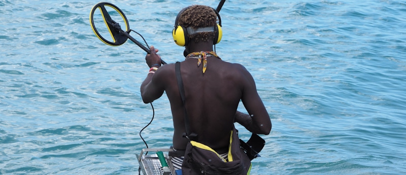 beach black men metal detector